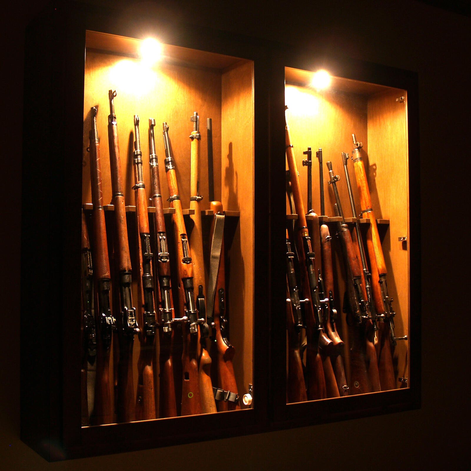 A residential gun cabinet at night — the long-term storage that complements rapid-access defensive staging