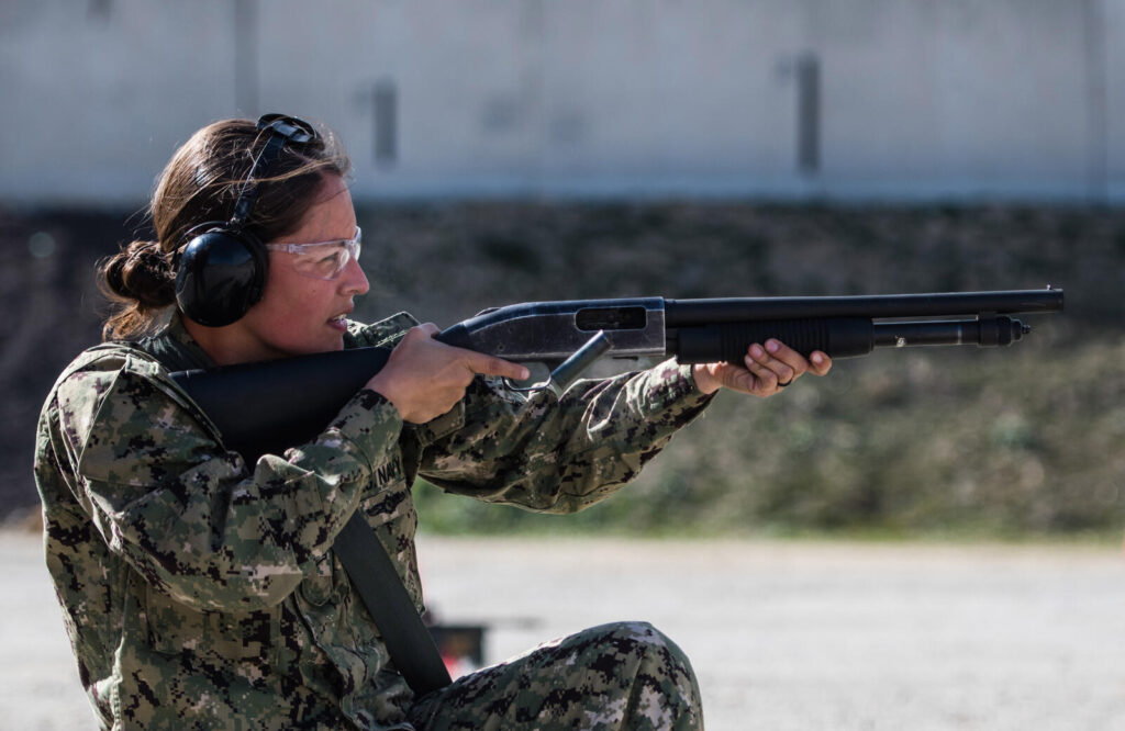 How to Choose a Gun for Self-Defense: Complete Guide (2026) 5 U.S. Navy Petty Officer 2nd Class Teresa Lopez-Webster firing a Mossberg 500 shotgun during qualification training