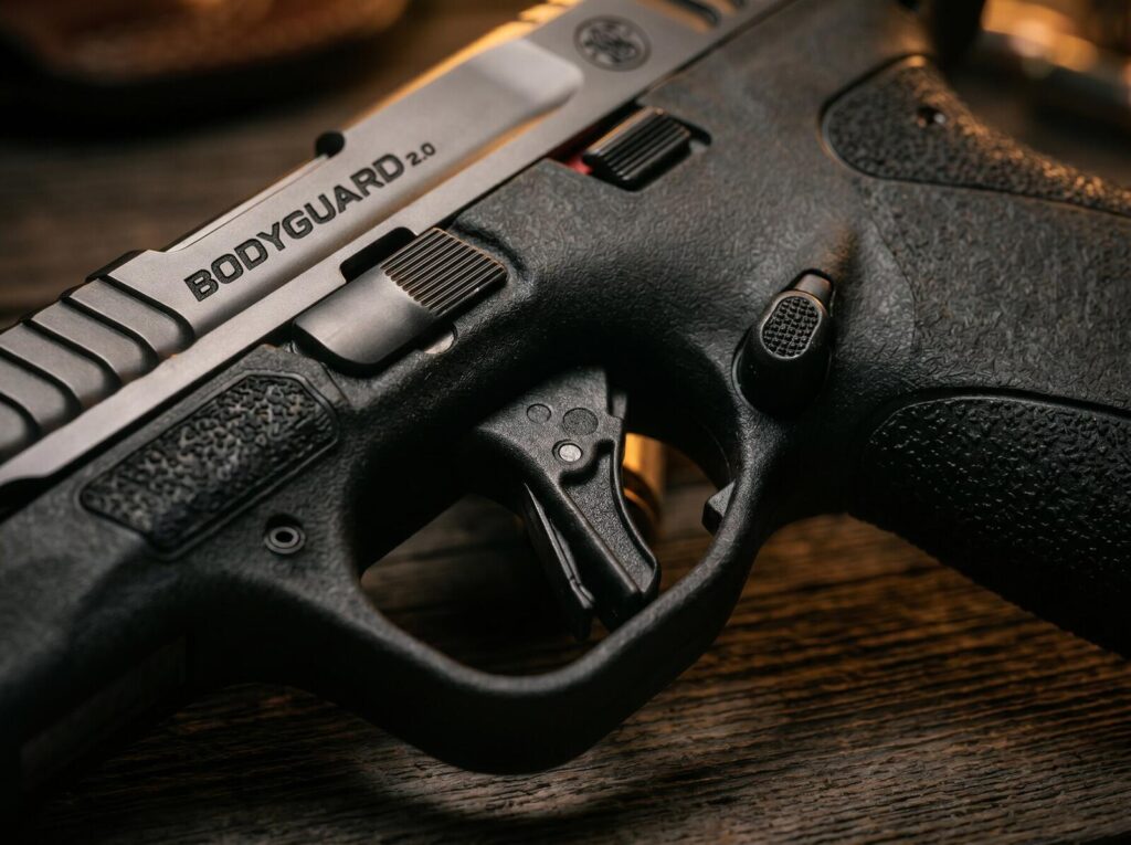 S&W M&P Bodyguard 2.0 Review (2026): 500 Round Test of the New Pocket .380 8 Macro detail of the flat-faced striker trigger and red-tipped manual safety lever on the Smith Wesson MP Bodyguard 2.0 pocket 380 ACP pistol