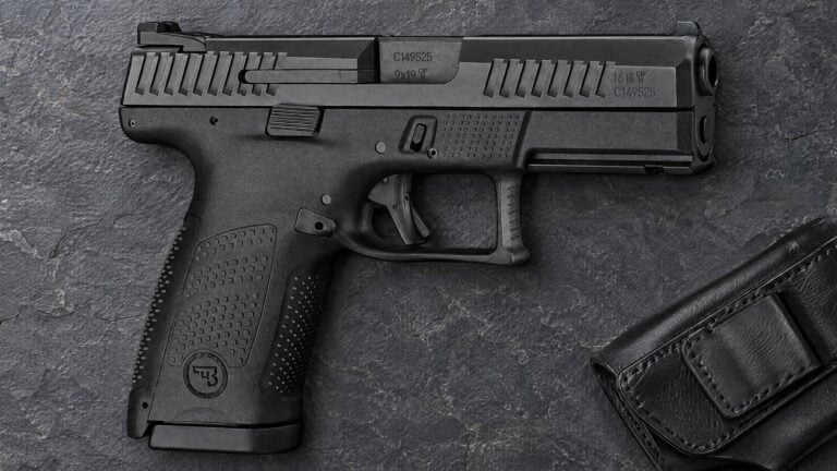 CZ P-10 C 9mm compact pistol lying flat on dark slate beside a black leather holster