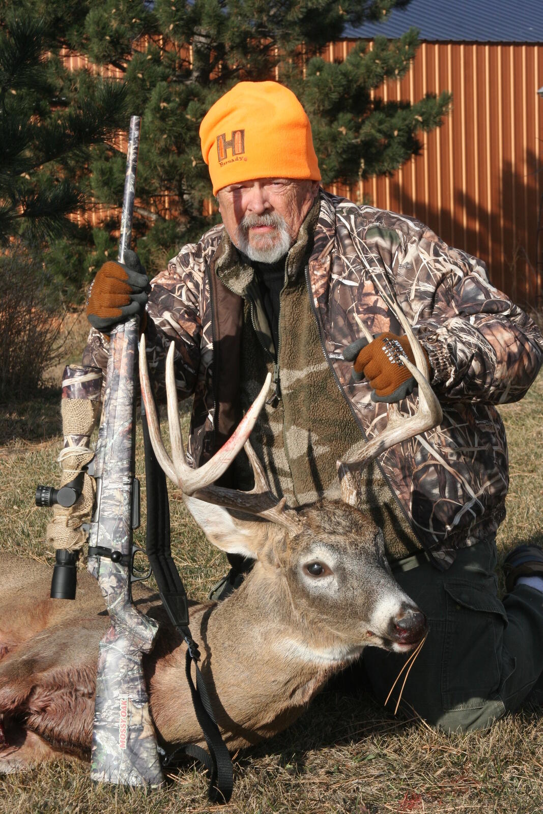 Hunting Safety Guide (2026): Treestand, Firearm, and Field Protocols 2 A hunter with rifle and a harvested white-tail deer — the firearm is the visible dimension of hunting safety but not the largest statistical risk