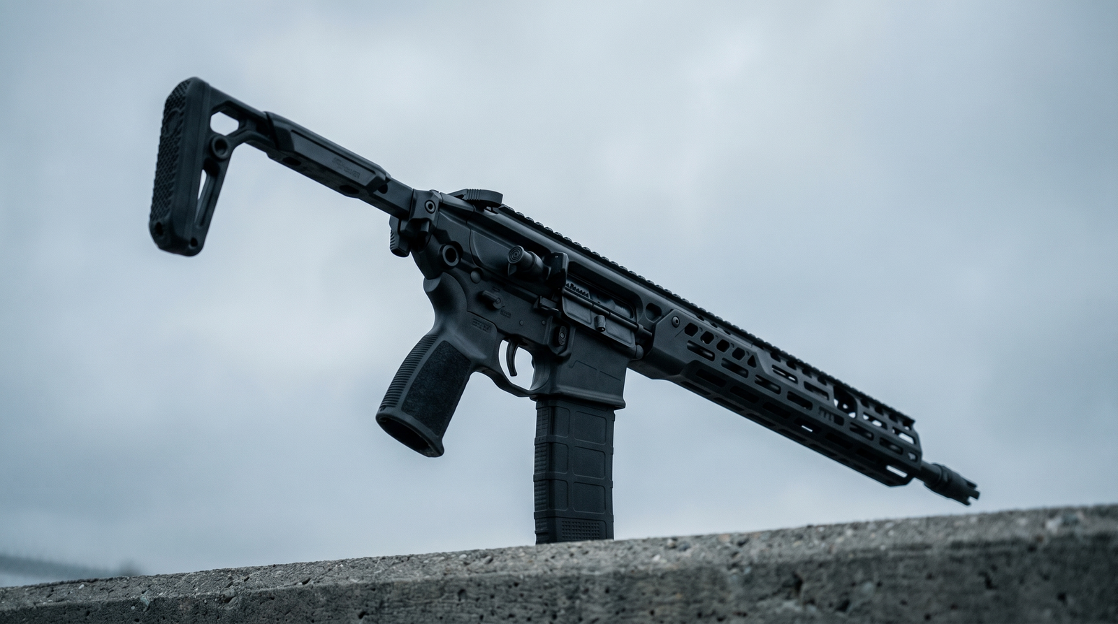 Sig MCX Spear LT Review (2026): 500 Round Test of the Next-Gen AR Alternative 2 Sig Sauer MCX Spear LT 5.56 NATO black rifle photographed from low ground-level angle against overcast cool grey sky on concrete urban tactical range pad with folded stock at left and dramatic monumental perspective