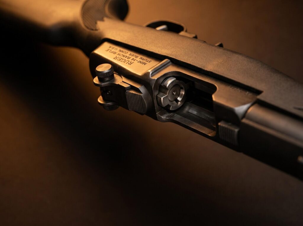 Ruger Mini-14 Review (2026): 500 Round Test of the Non-Scary AR Alternative 7 Macro detail of the Garand-style rotating bolt and forged-steel receiver markings on the Ruger Mini-14 Ranch Rifle in warm tungsten rim lighting