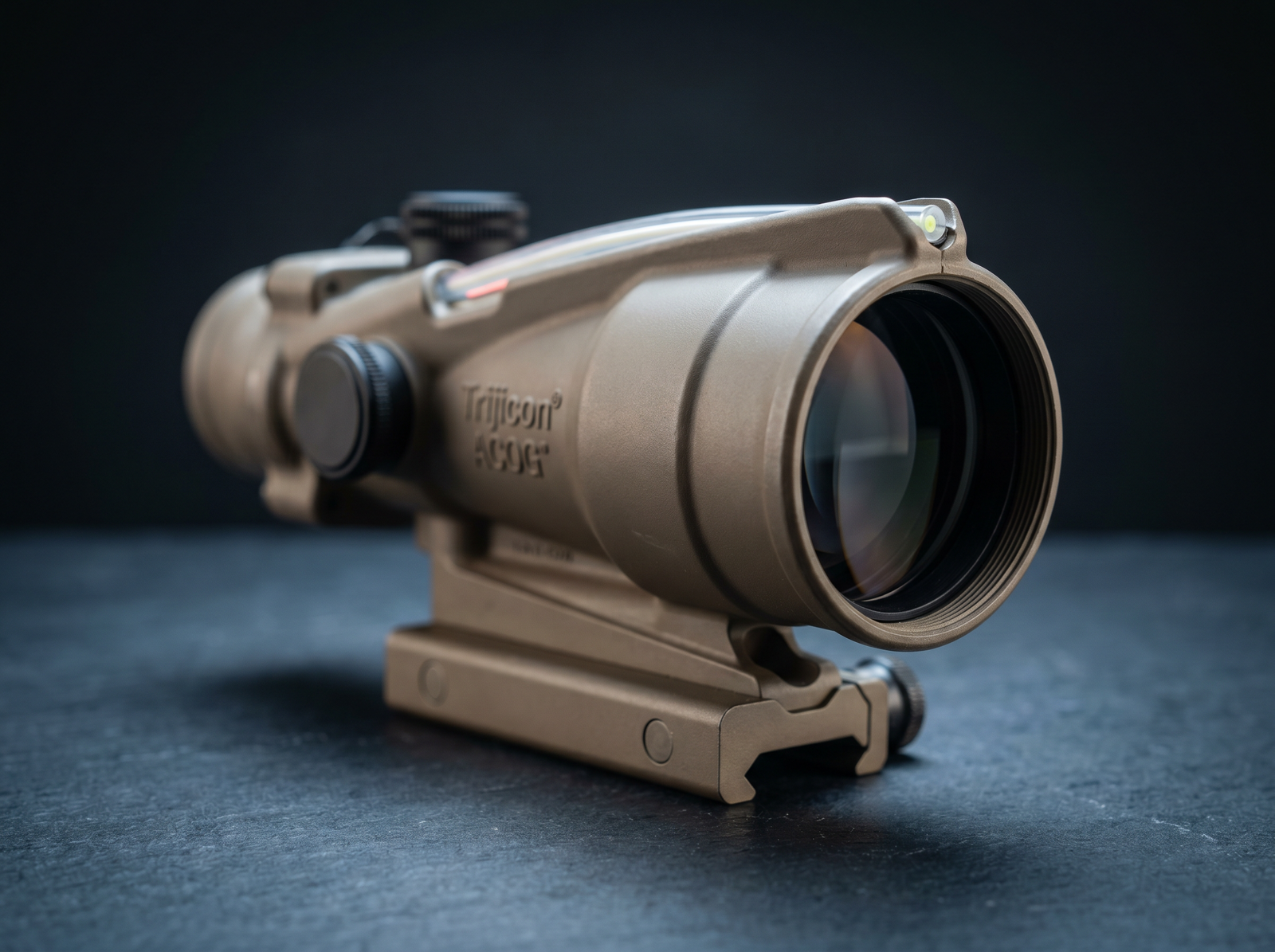 8 Best Prism Scopes in 2026: Tested and Ranked 28 Extreme macro three-quarter front studio close-up of Trijicon ACOG TA31 4x32 prism scope with tan anodized aluminum housing, raised fiber-optic top illumination strip, large 32mm objective lens, mounted on quick-detach base on dark slate backdrop with cool overhead key light and rim highlights along housing edge