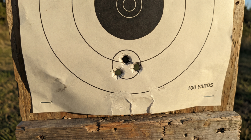 Savage 220 9 Paper bullseye target at 100 yards on a weathered wooden frame showing a tight sub-MOA three-shot group from the Savage 220 with Federal Trophy Copper sabot slugs