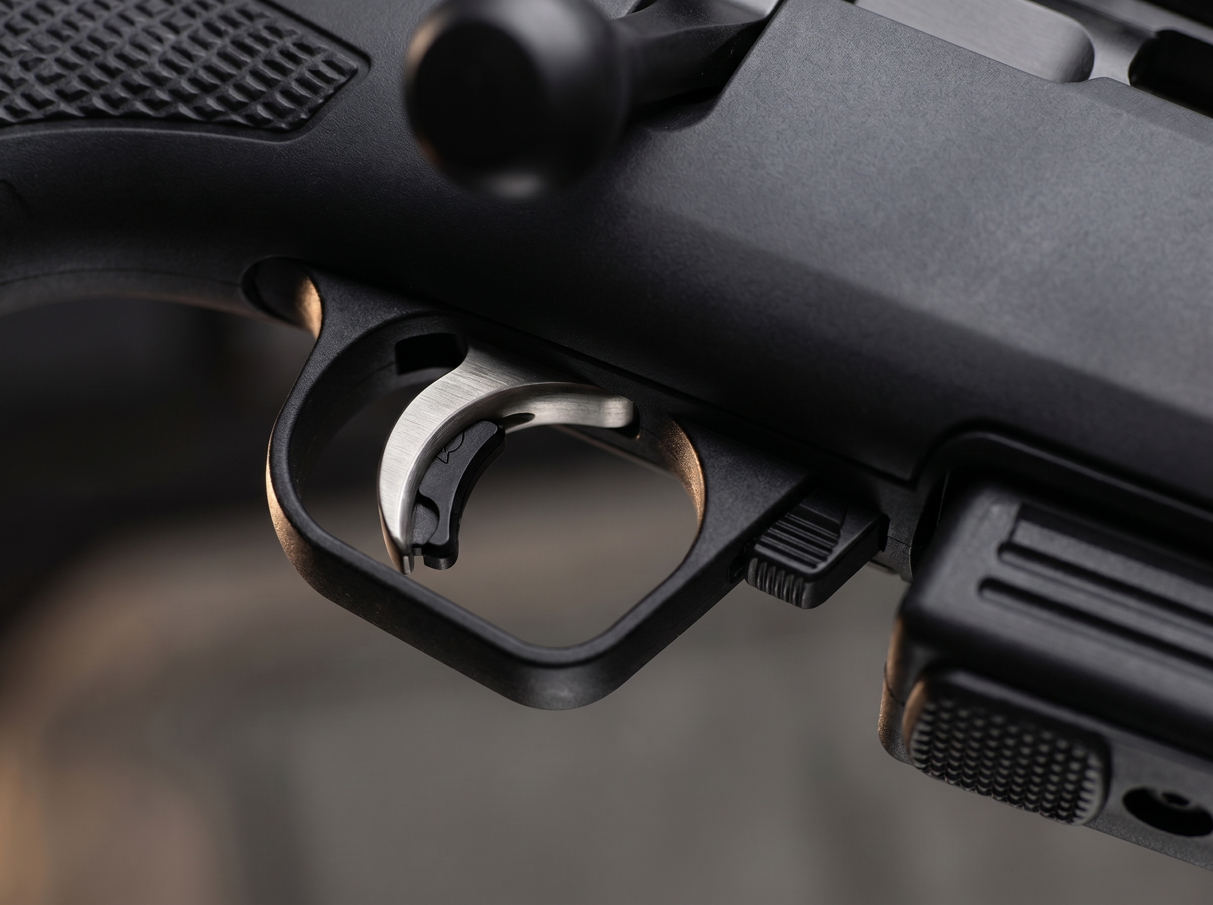 Macro close-up of the AccuTrigger and AccuRelease safety blade on the Savage 220 bolt-action slug gun with the magazine release button visible to the right