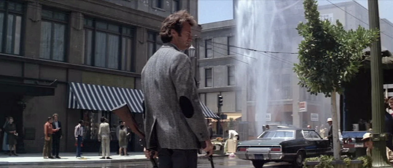 Harry Callahan carrying the robbers Winchester Model 12 shotgun away from the bank robbery scene in Dirty Harry