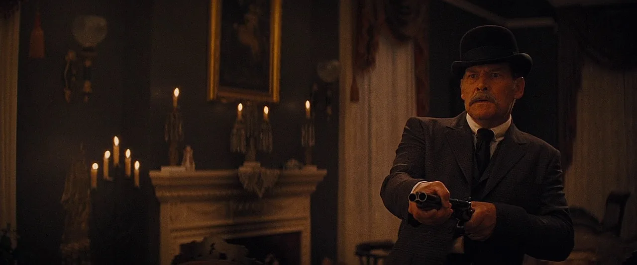 Butch Pooch holding a sawed-off double-barrel percussion shotgun with his hand at the muzzle in Django Unchained