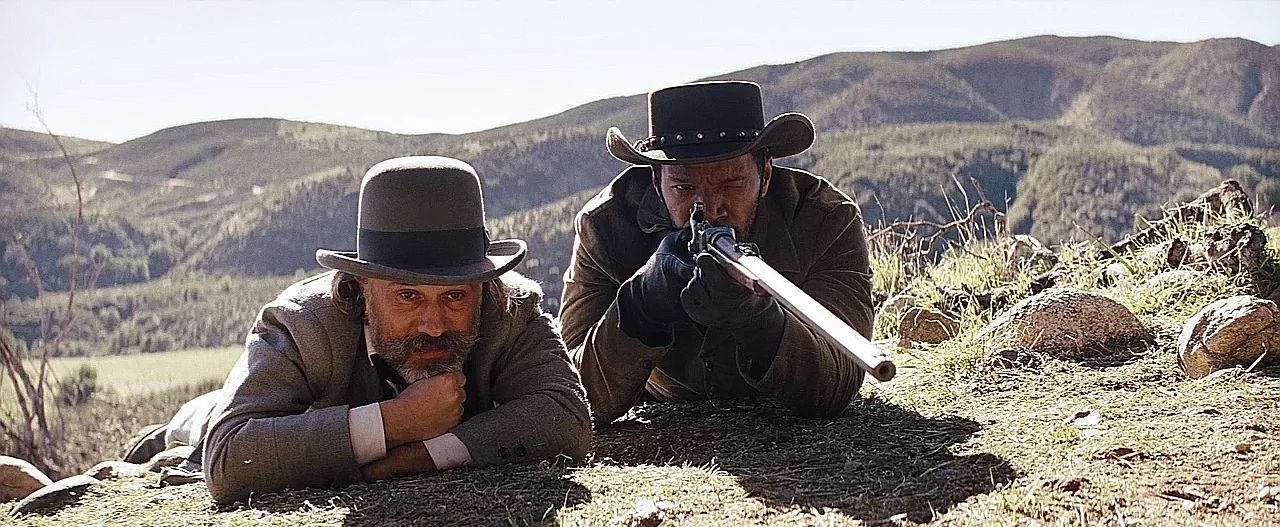 Django taking aim with the Sharps 1874 buffalo rifle beside Dr King Schultz in Django Unchained