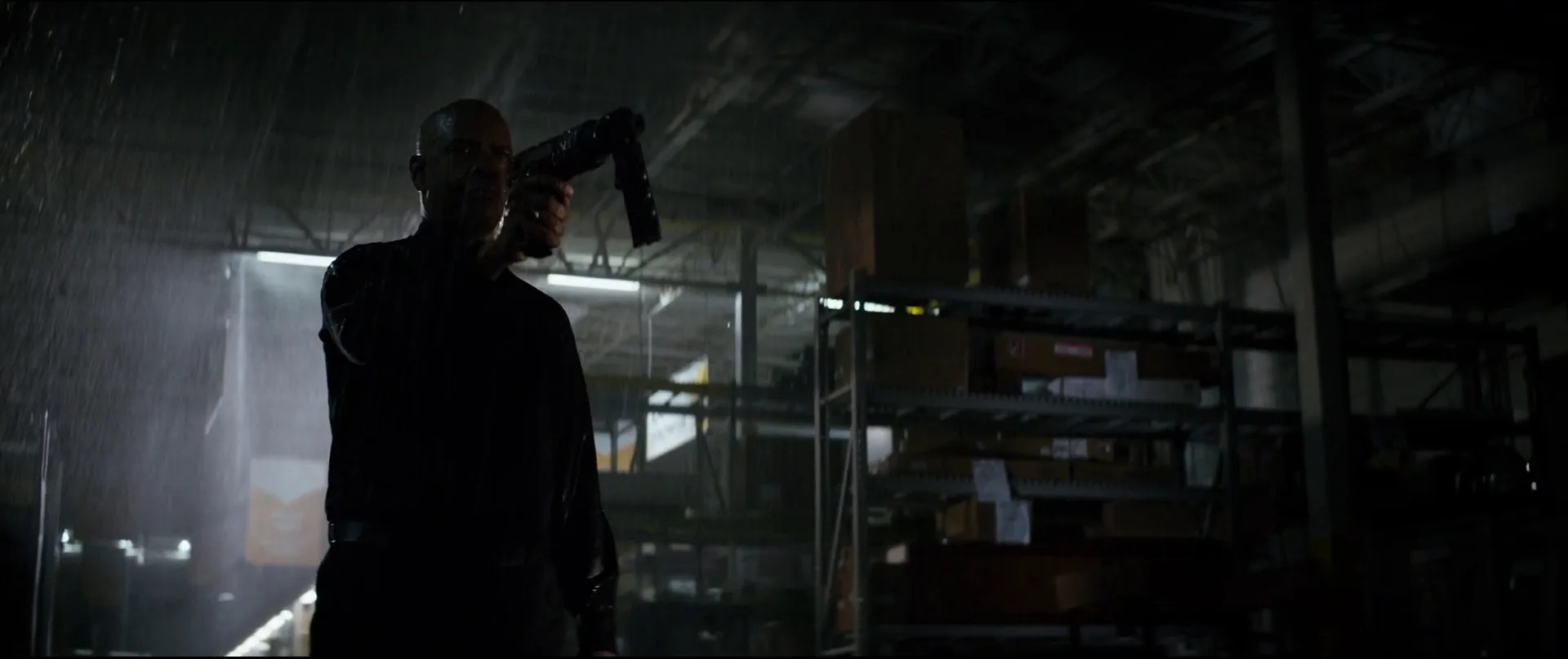 Robert McCall holding a pneumatic nail gun two-handed in the sprinkler-soaked Home Mart in The Equalizer