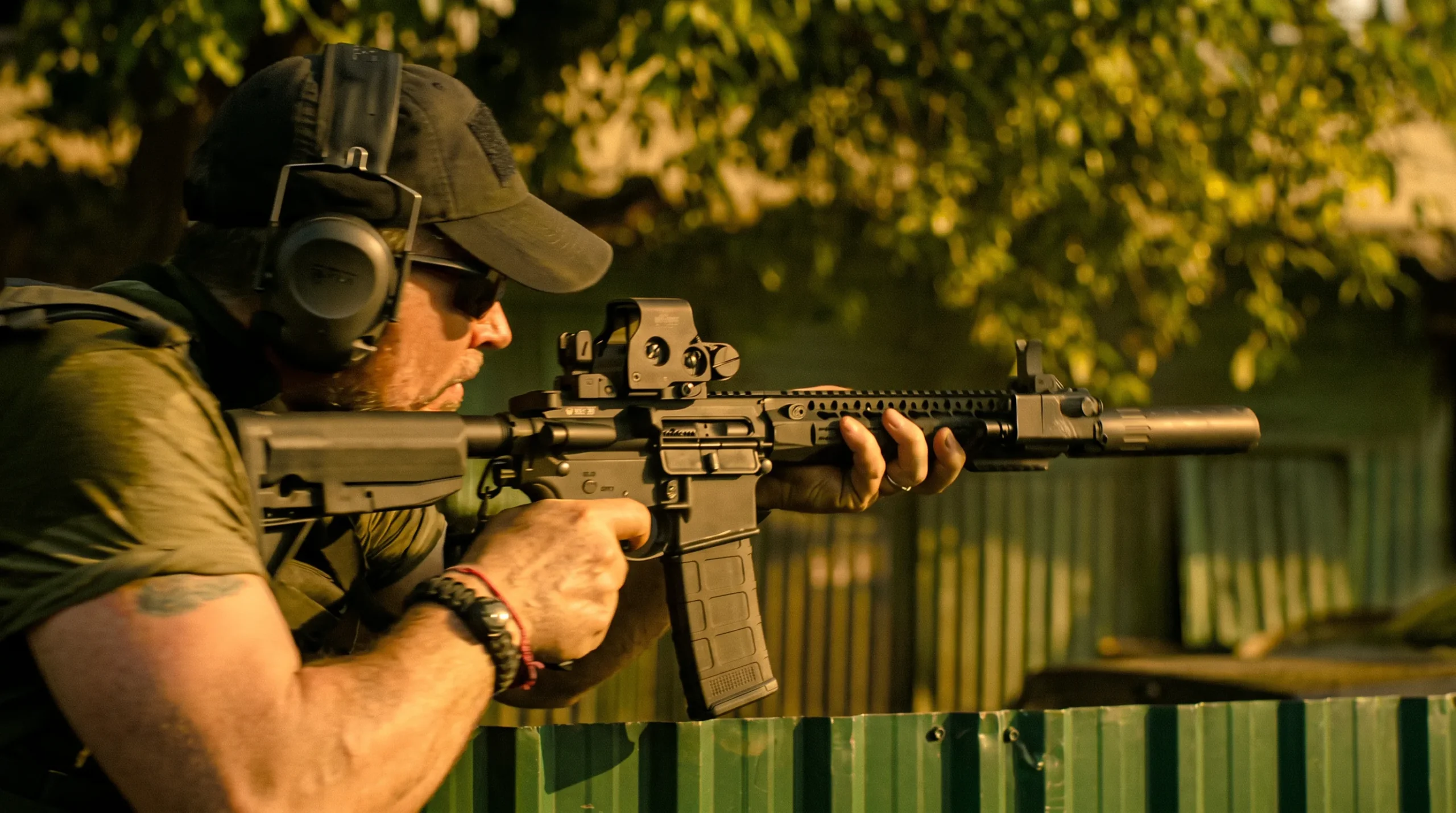 A mercenary aiming a suppressed carbine with a red dot sight in Extraction