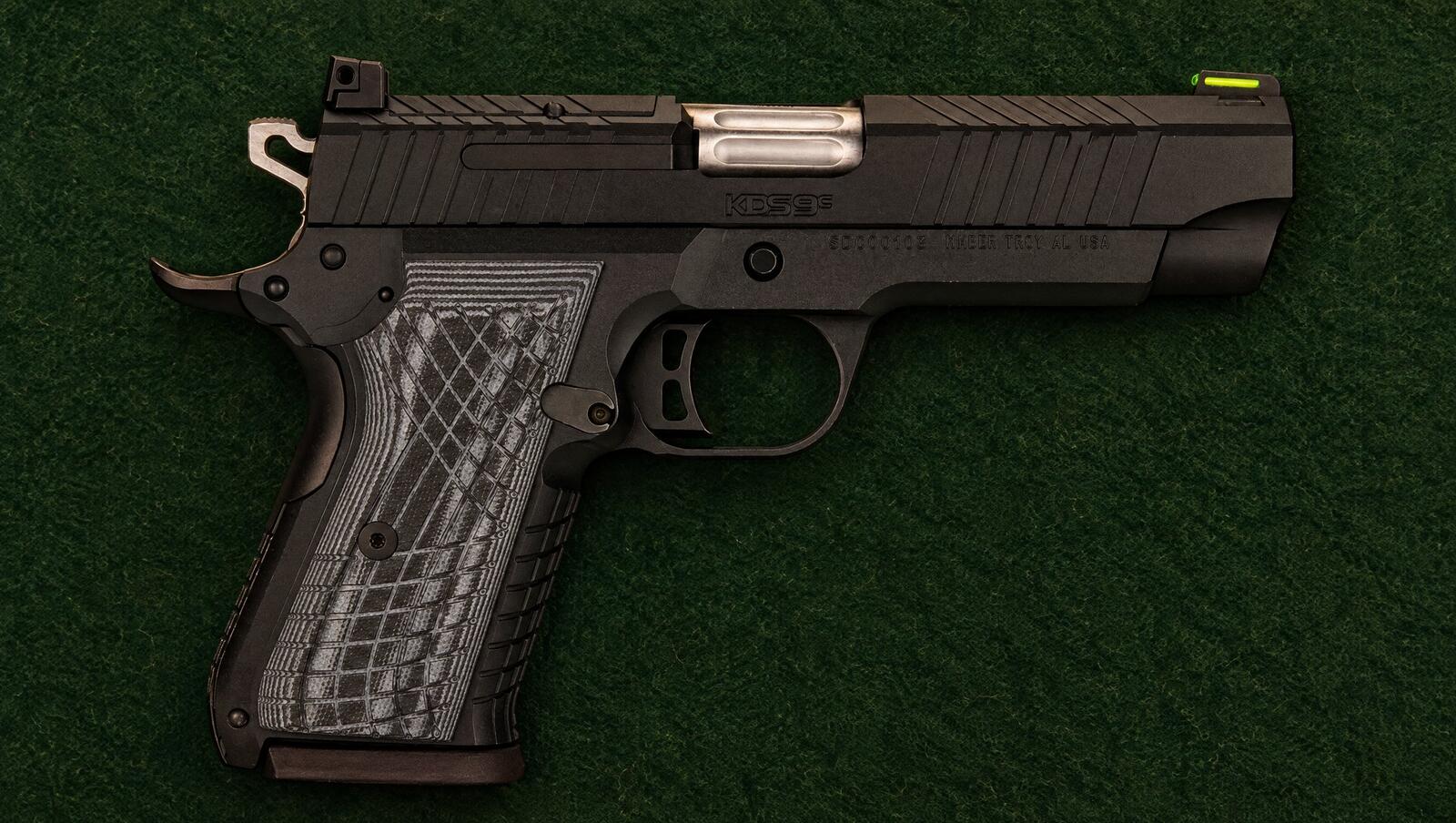 Kimber KDS9c compact double stack 1911 lying on dark green felt in warm lamp light