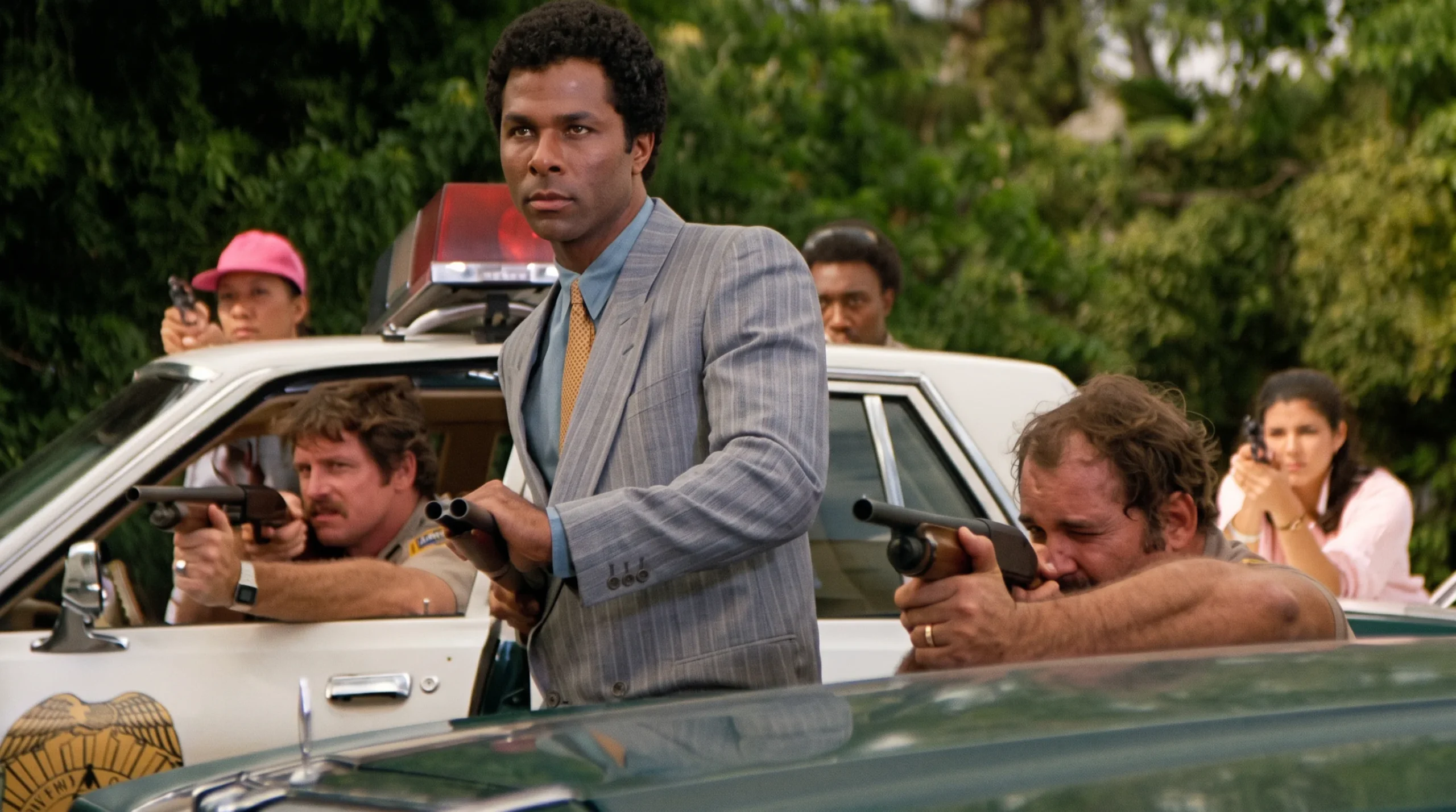 Ricardo Tubbs holding a shotgun behind a squad car in Miami Vice
