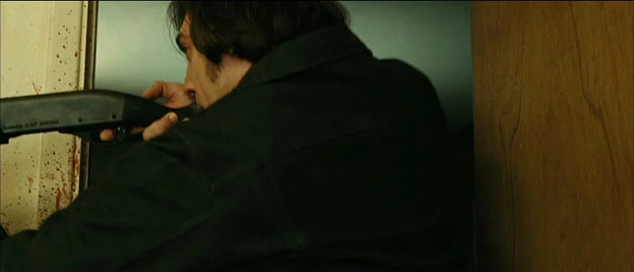 Anton Chigurh shouldering his suppressed Remington 11-87 semi-automatic shotgun in No Country for Old Men