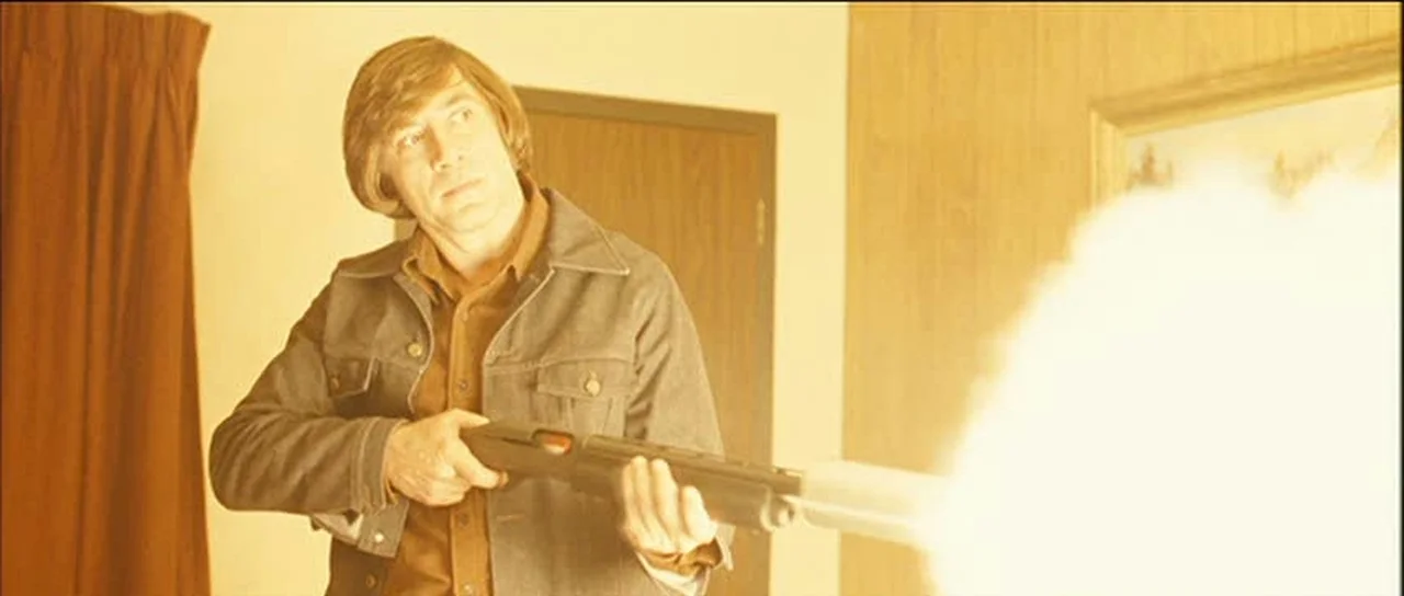 Anton Chigurh firing his suppressed shotgun with a huge muzzle flash lighting the room in No Country for Old Men