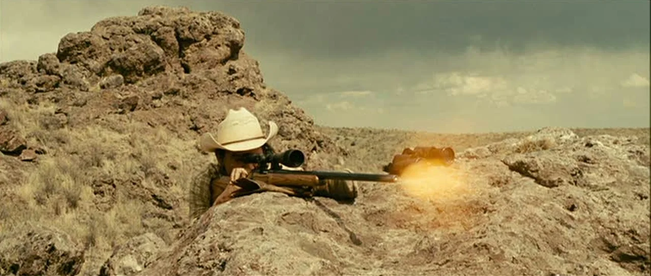Llewelyn Moss firing his scoped Remington 700 rifle prone in the desert at a pronghorn in No Country for Old Men