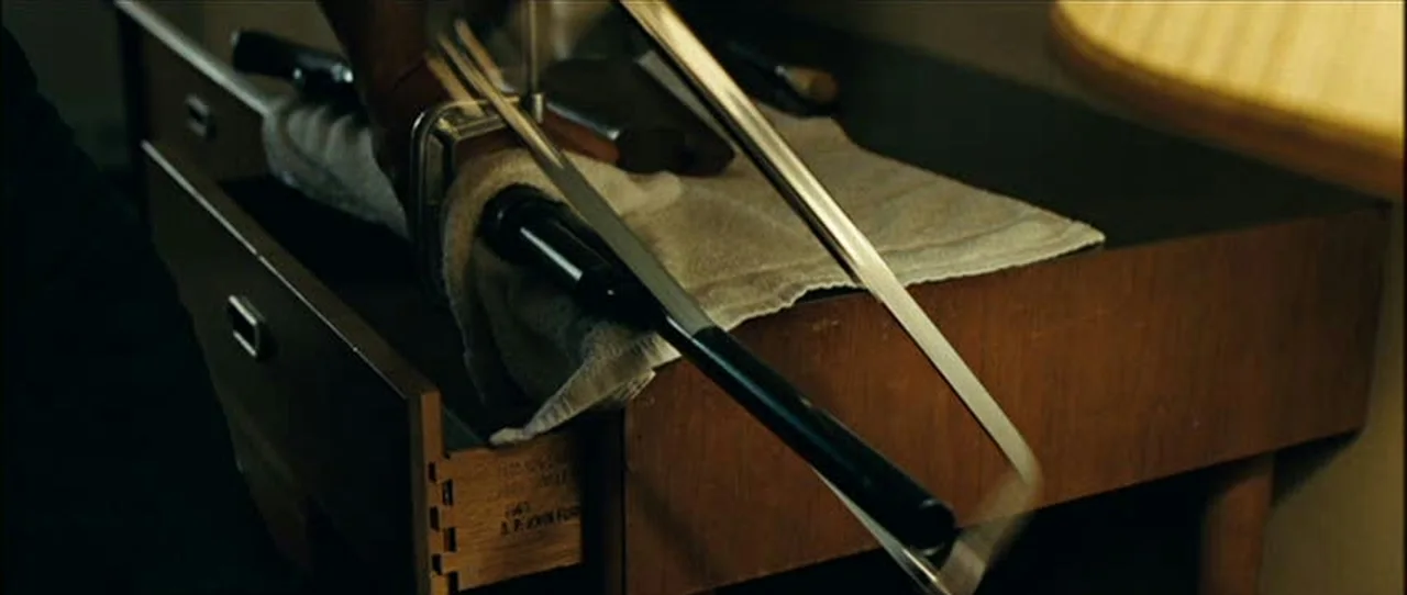 Llewelyn Moss sawing the barrel off his Winchester Model 1897 shotgun on a motel dresser in No Country for Old Men