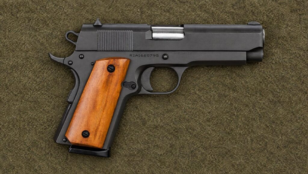 A Rock Island 1911 .45 pistol with wood grips lying flat on an olive wool blanket