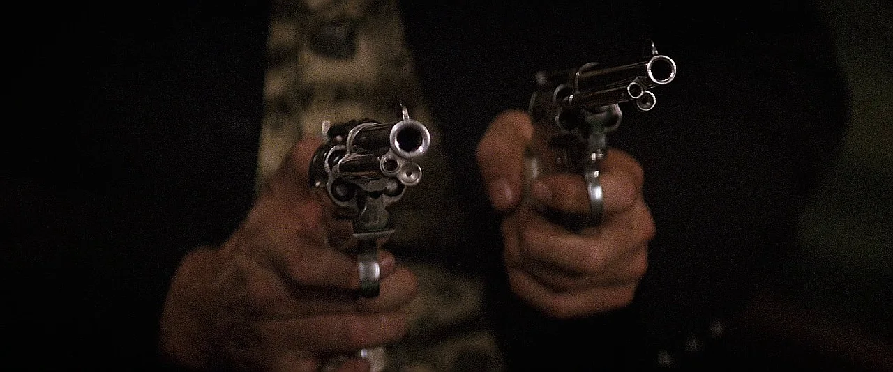 Doc Holliday pointing his Colt Single Action Army and Colt Lightning at the camera in Tombstone