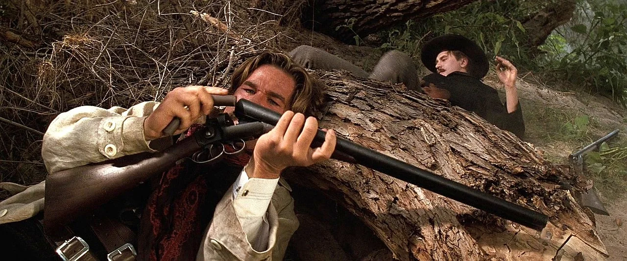 Wyatt Earp loading his Stevens 10-gauge side-by-side shotgun behind a log at Iron Springs in Tombstone