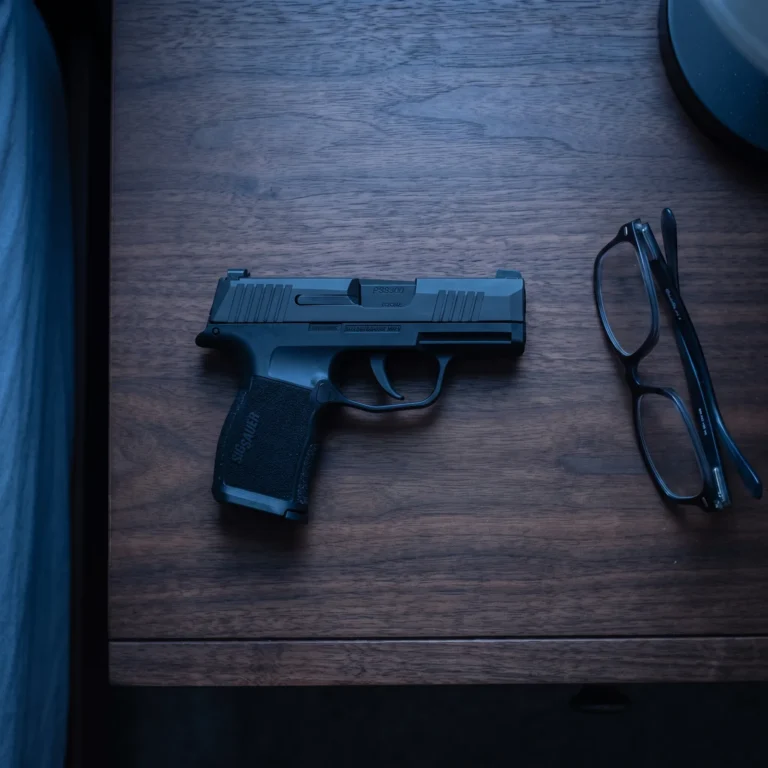 Sig Sauer P365 micro-compact 9mm pistol on a dark walnut nightstand at blue hour