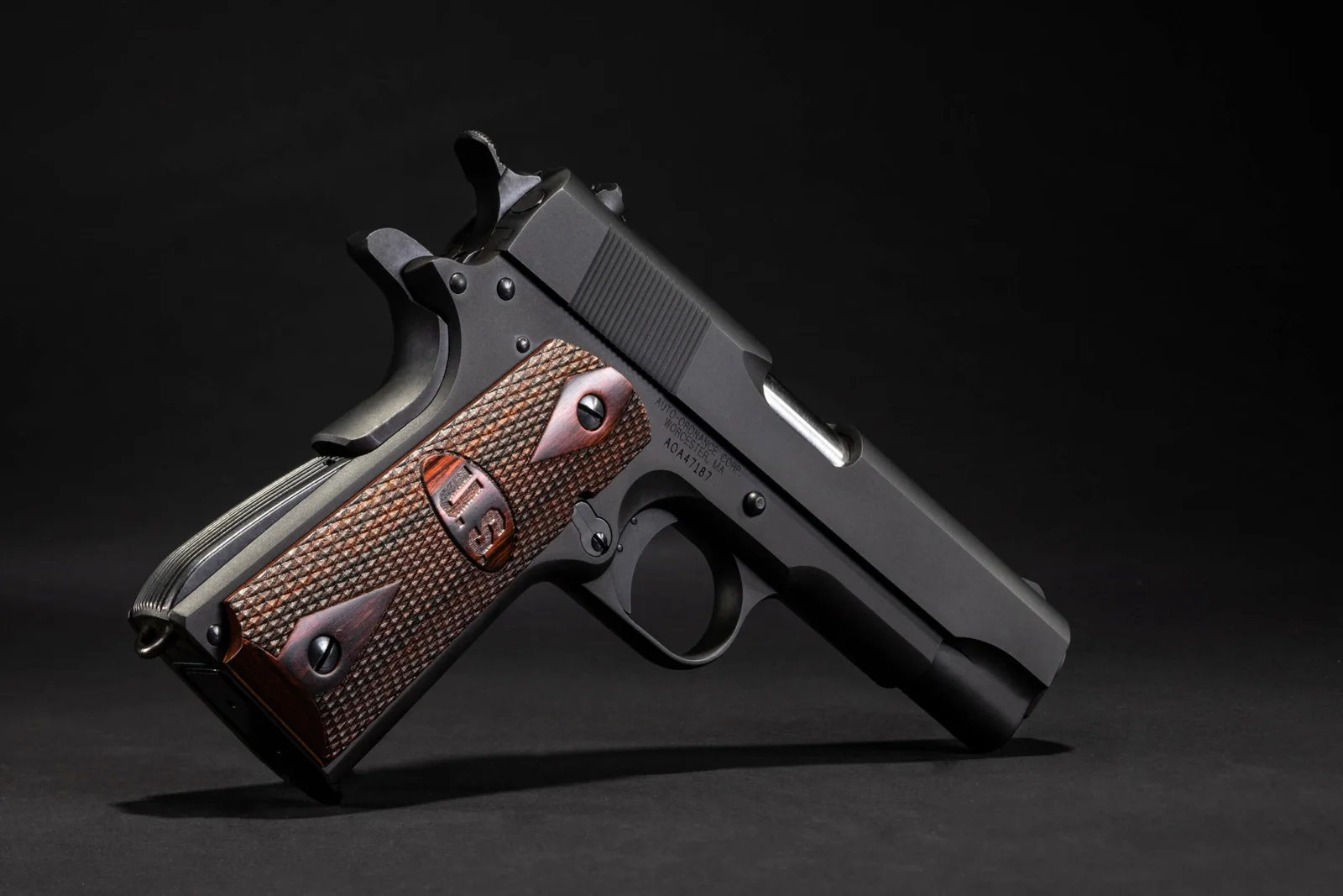 Auto-Ordnance 1911BKOWC Commander .45 ACP with checkered wood U.S. logo grips, studio photo on a dark background