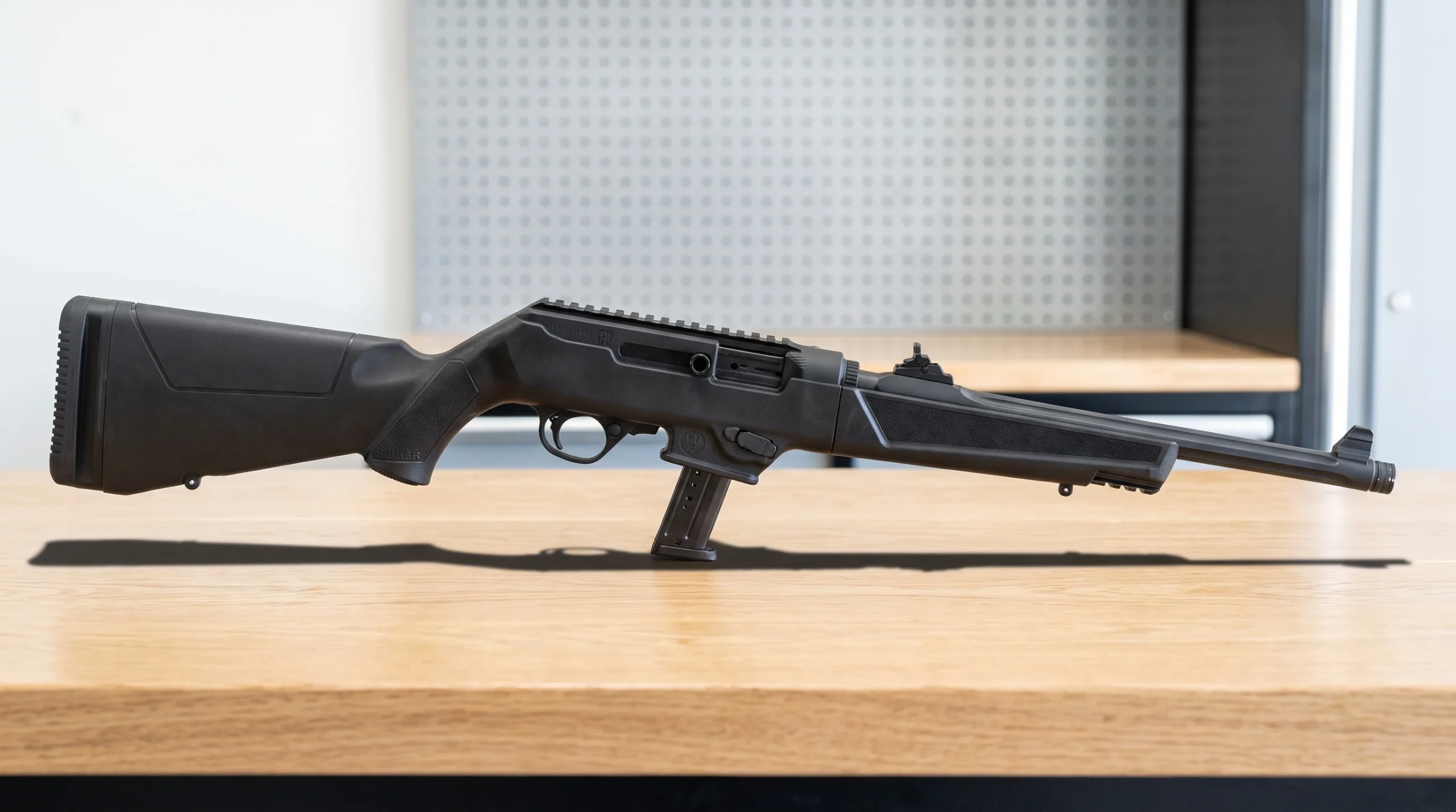 Ruger PC Carbine resting on a clean white oak workbench in a bright modern garage workshop