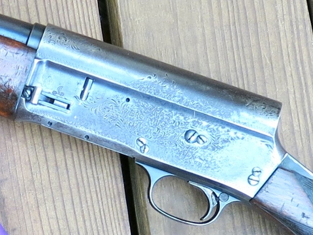 Left side of a Browning Auto-5 receiver showing the magazine cutoff lever and worn scroll engraving