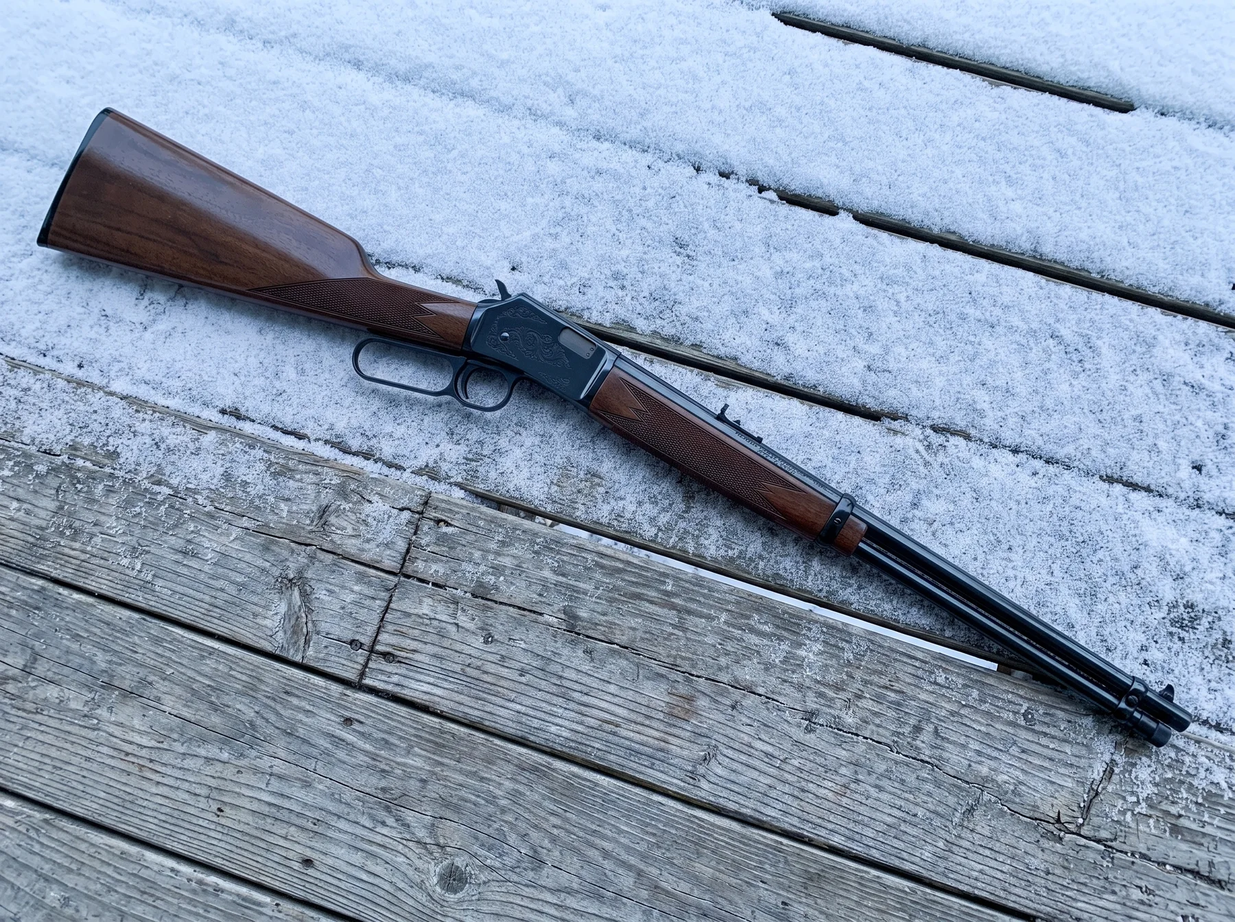 Browning BL-22 Grade II with engraved receiver and checkered walnut on snowy porch boards, seen from above