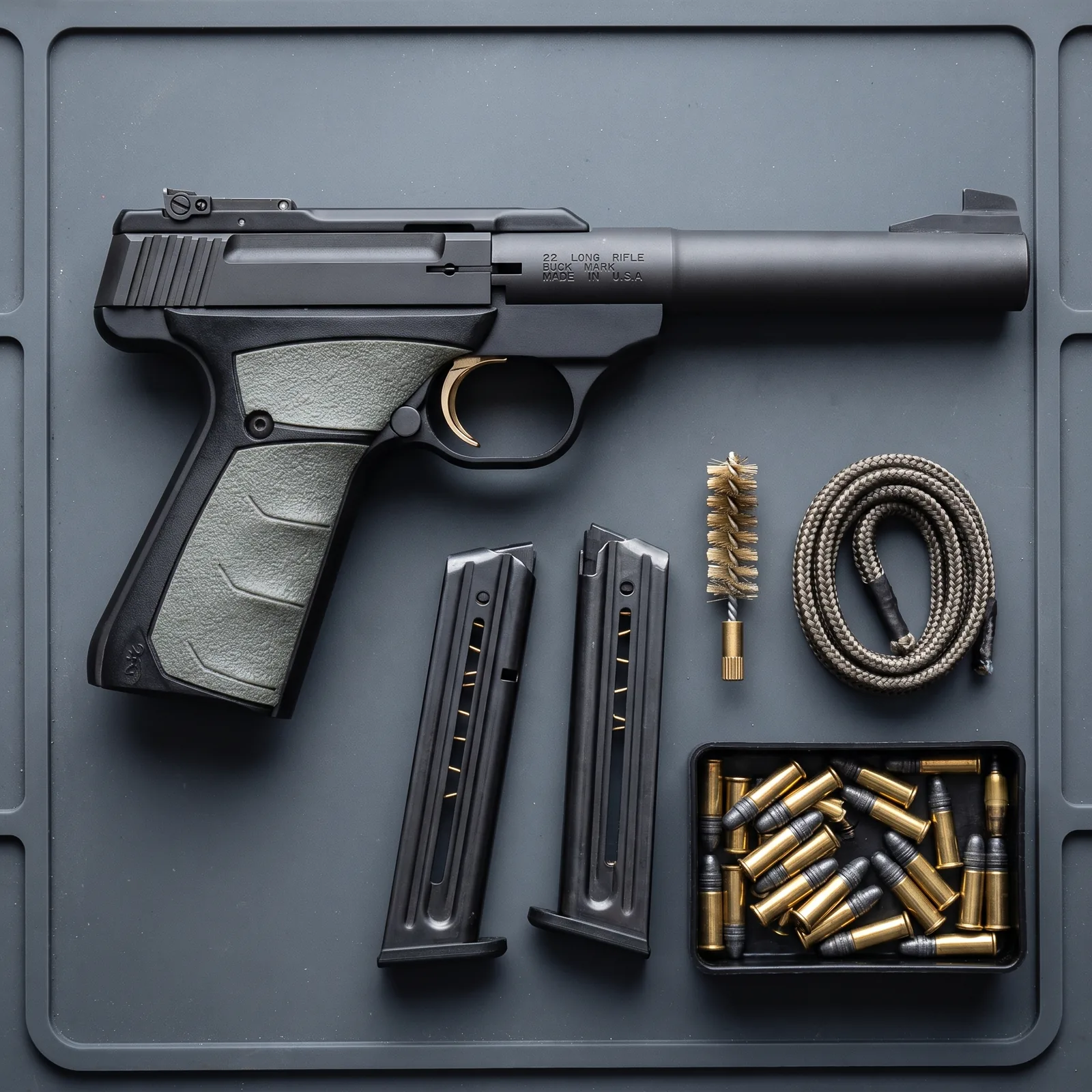 Browning Buck Mark laid out on a bench mat with two spare magazines, cleaning kit and .22 LR rounds