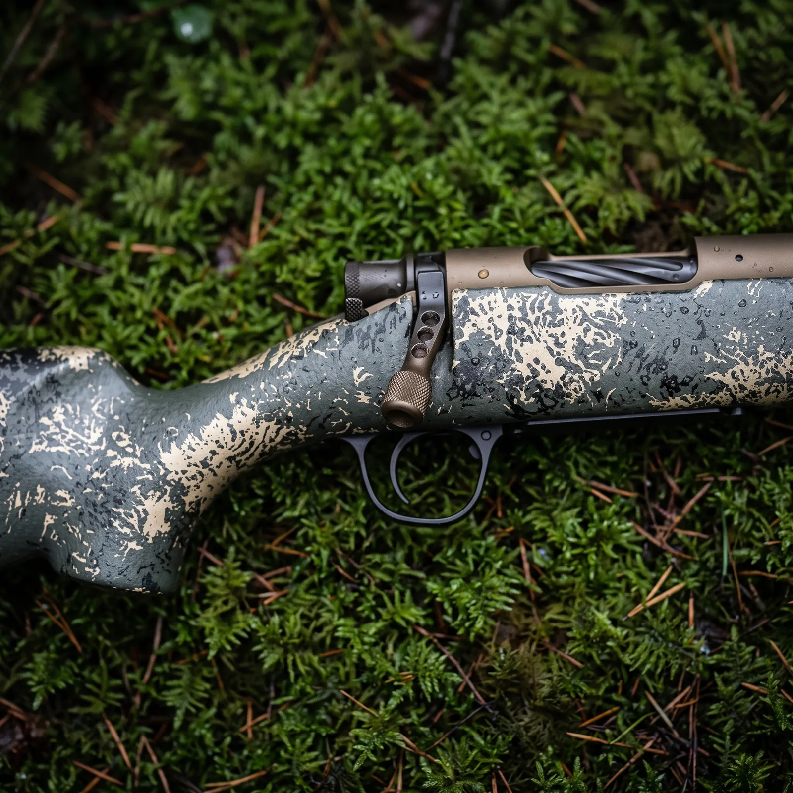 Close up of the Christensen Arms Mesa FFT receiver, bolt handle and carbon fiber stock on damp moss
