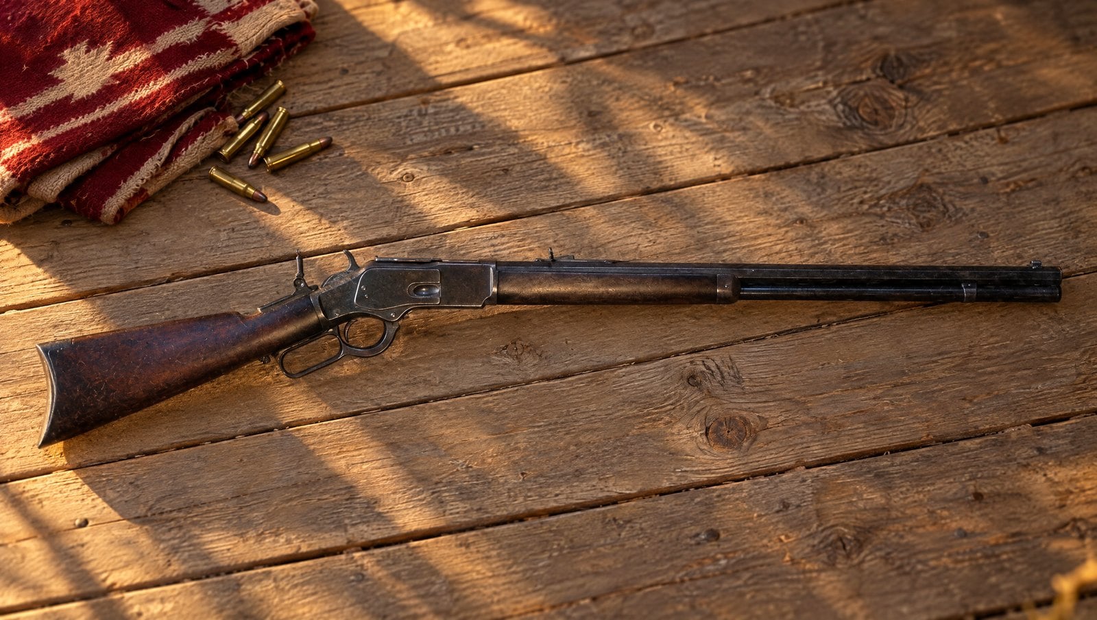 Classic American rifles: an original Winchester Model 1873 lever-action rifle on a sunlit plank porch beside a wool blanket