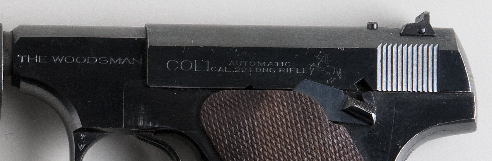 Left side of a Colt Woodsman showing THE WOODSMAN frame stamp, COLT AUTOMATIC slide roll mark and rampant colt logo