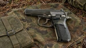 Czechoslovak CZ 82 surplus pistol on a camouflage tarp at a forest bivouac
