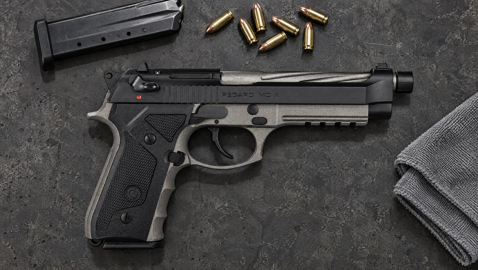 Girsan Regard MC X 9mm pistol with tungsten frame and threaded barrel lying on a concrete workbench beside a spare magazine and 9mm cartridges