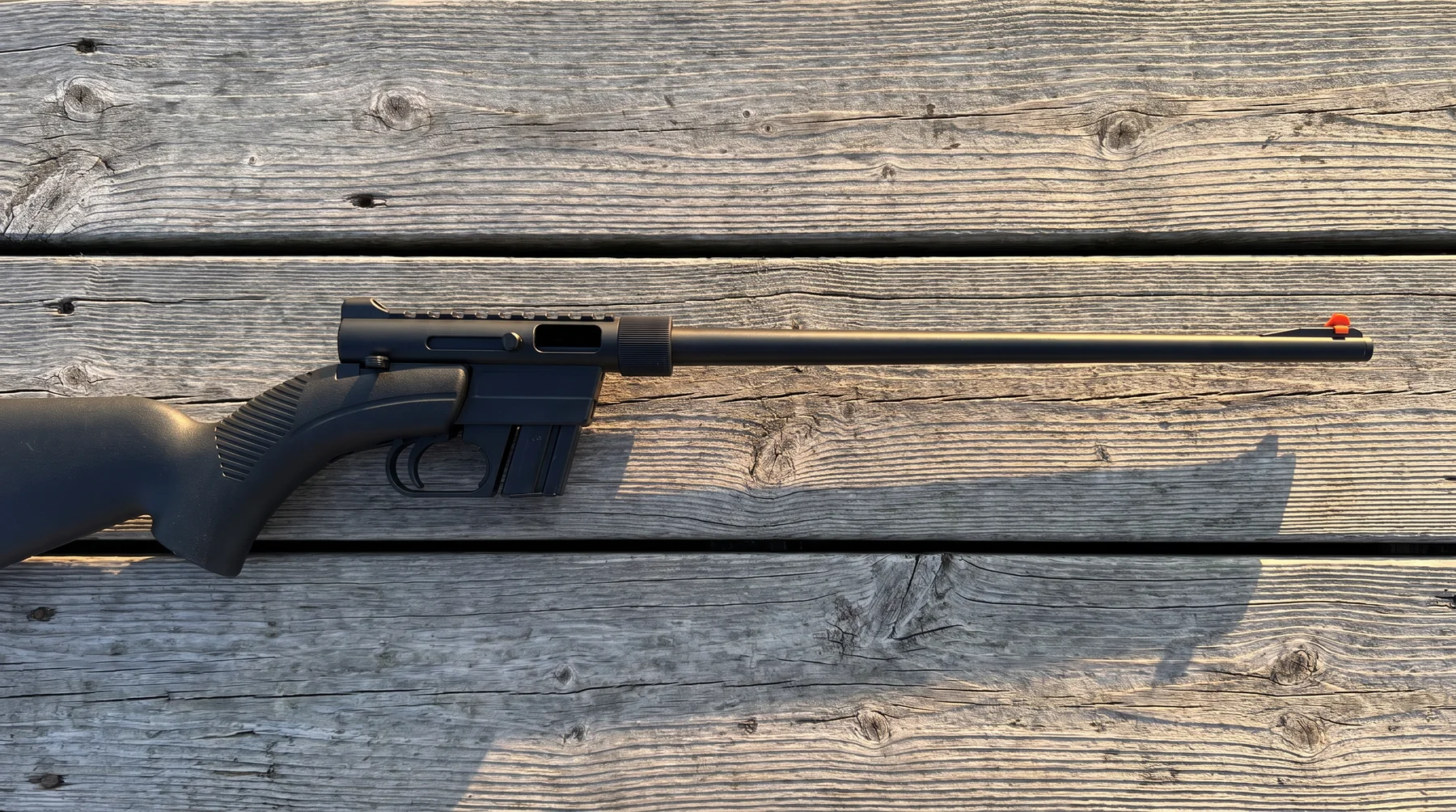 Henry U.S. Survival AR-7 rifle lying on weathered dock planks at sunrise, seen from above
