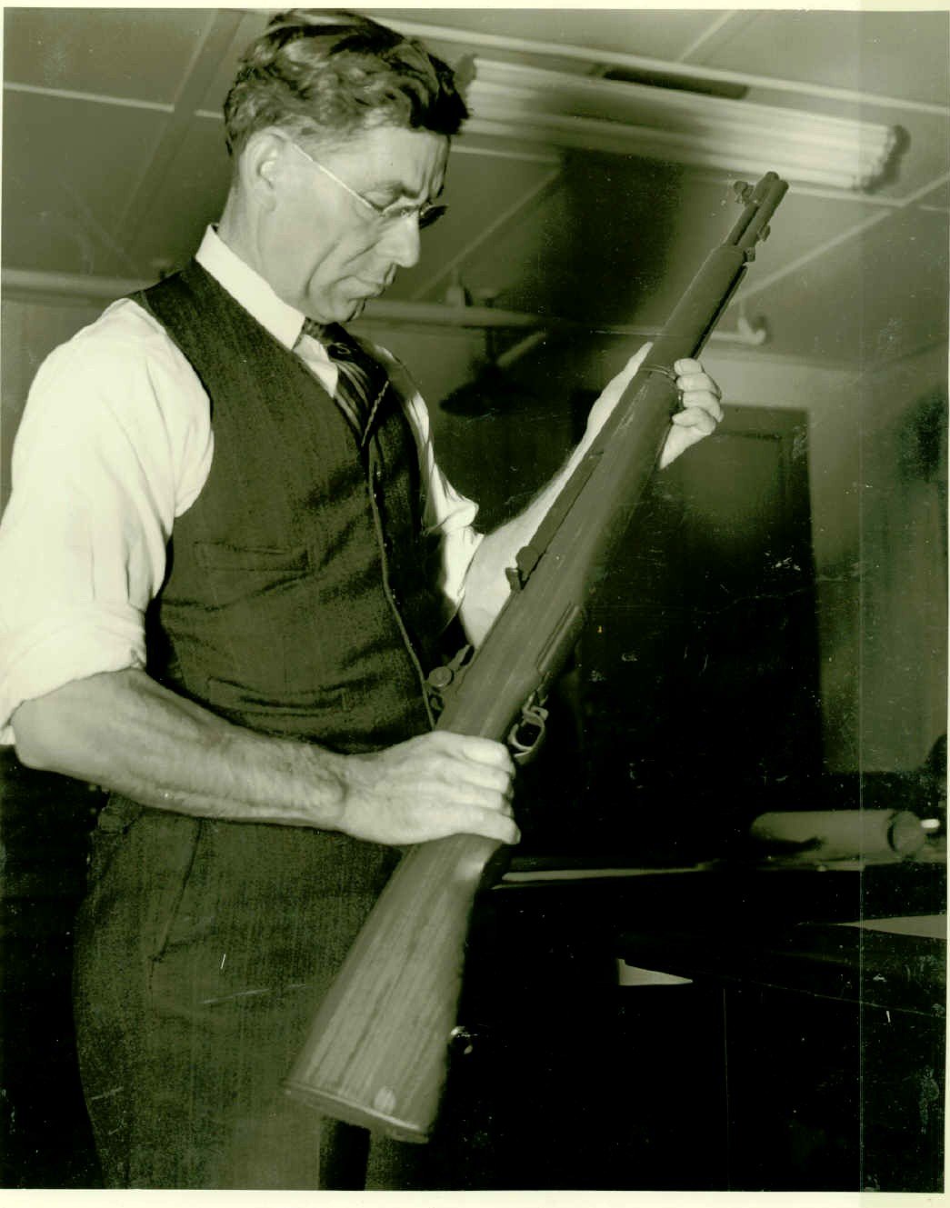 Designer John C. Garand holding the M1 rifle at Springfield Armory, black and white photograph