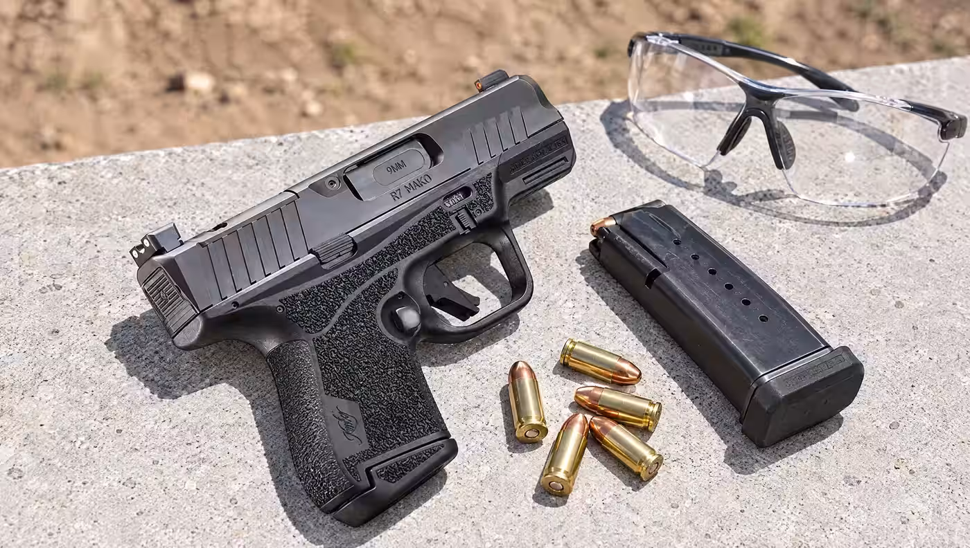 Kimber R7 Mako optics-ready pistol on a concrete range bench beside a spare magazine, loose 9mm cartridges and shooting glasses