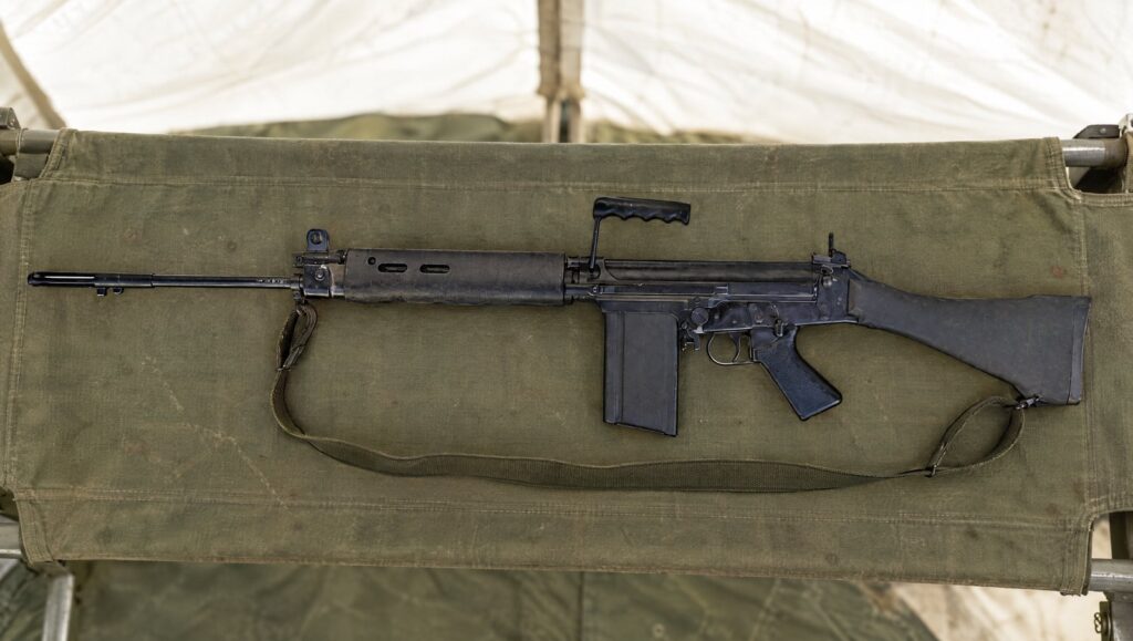 L1A1 self-loading rifle on a green canvas stretcher in a field hospital tent