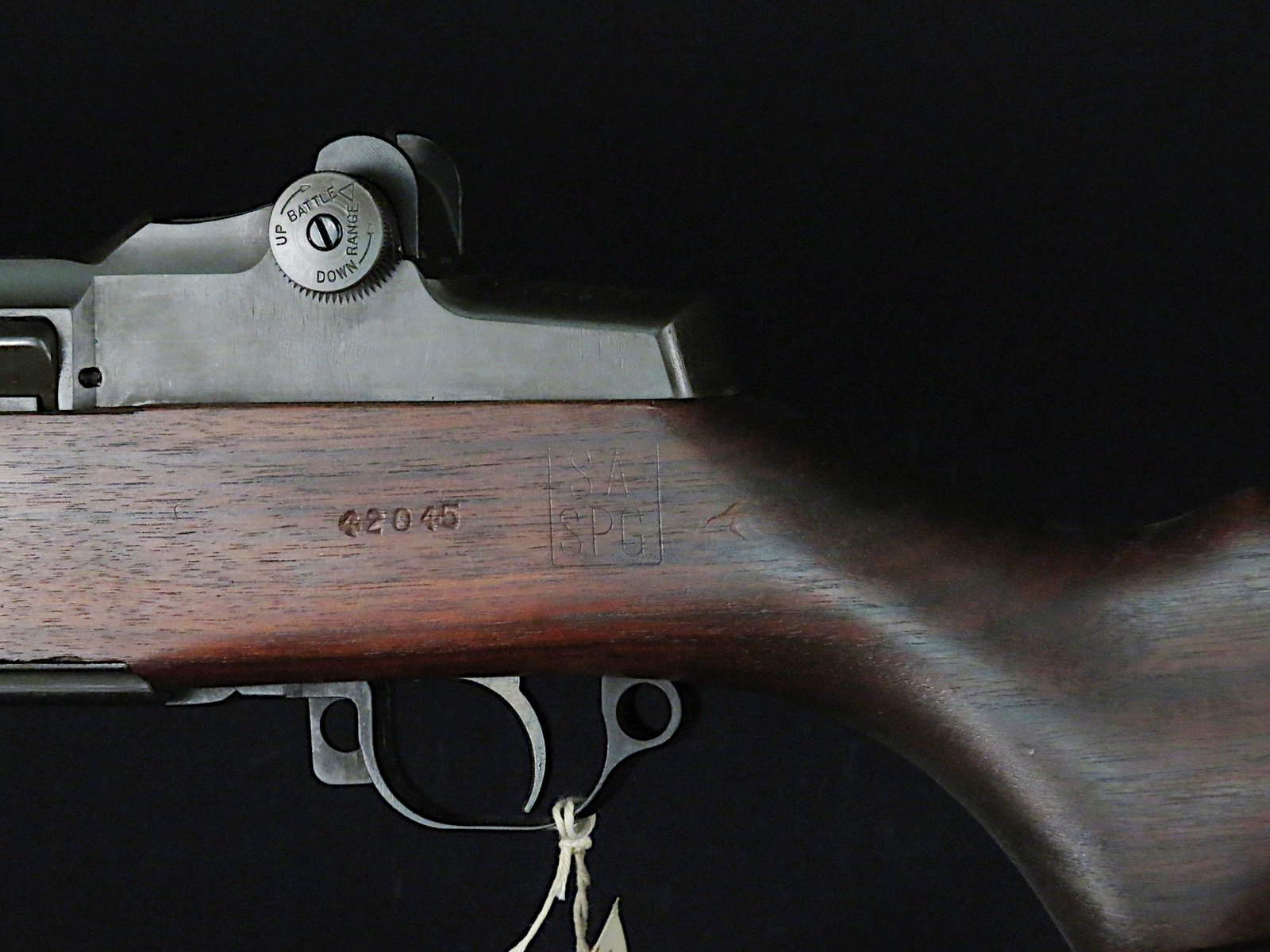 Left side of an M1 Garand stock showing the boxed SA SPG inspector cartouche, a stamped number and the rear sight windage knob
