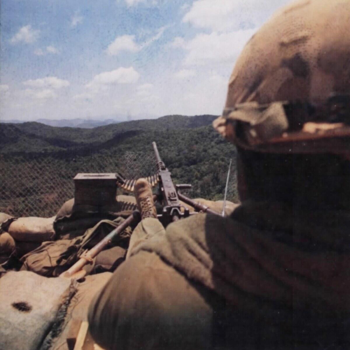 An American soldier behind an M2 Browning .50 caliber machine gun on a sandbagged firebase perimeter in Vietnam