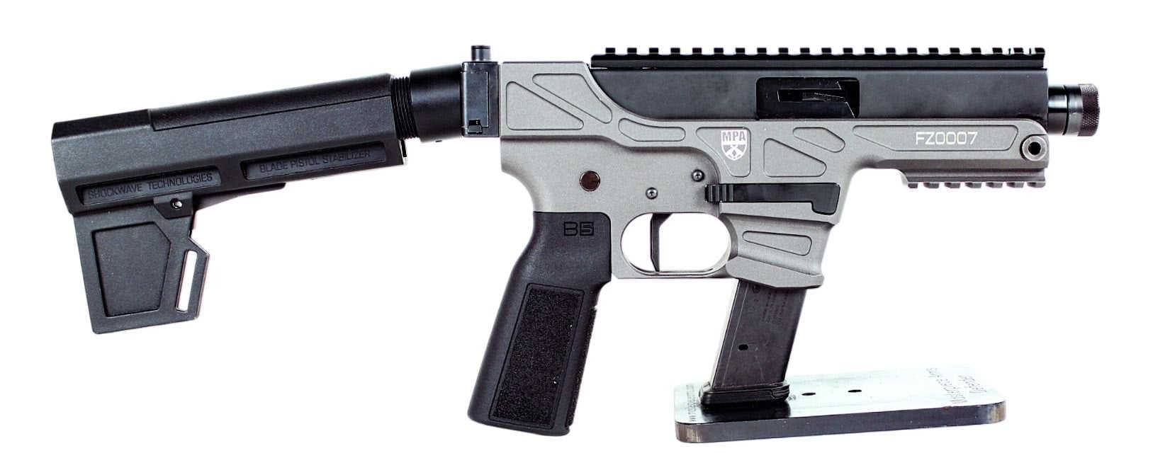 Masterpiece Arms Defender 30K 9mm pistol in black and gray with a folding brace, Glock-pattern magazine and top rail, on a stand