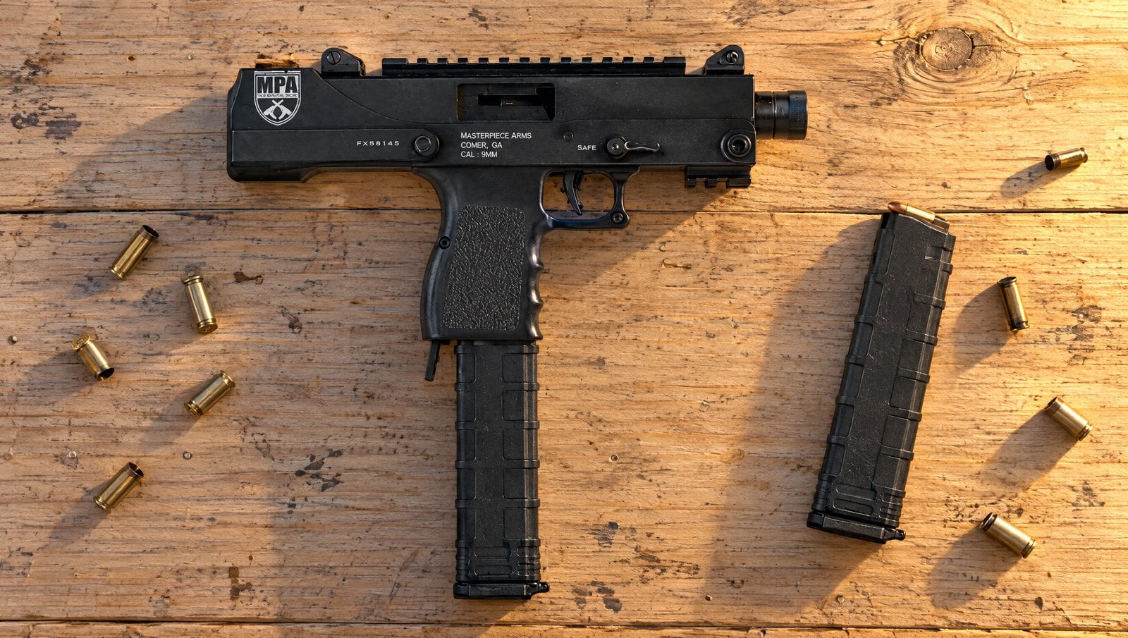 Masterpiece Arms MPA30SST 9mm side-cocking pistol with a top Picatinny rail lying on a pine range bench with spent brass and a spare 30-round magazine