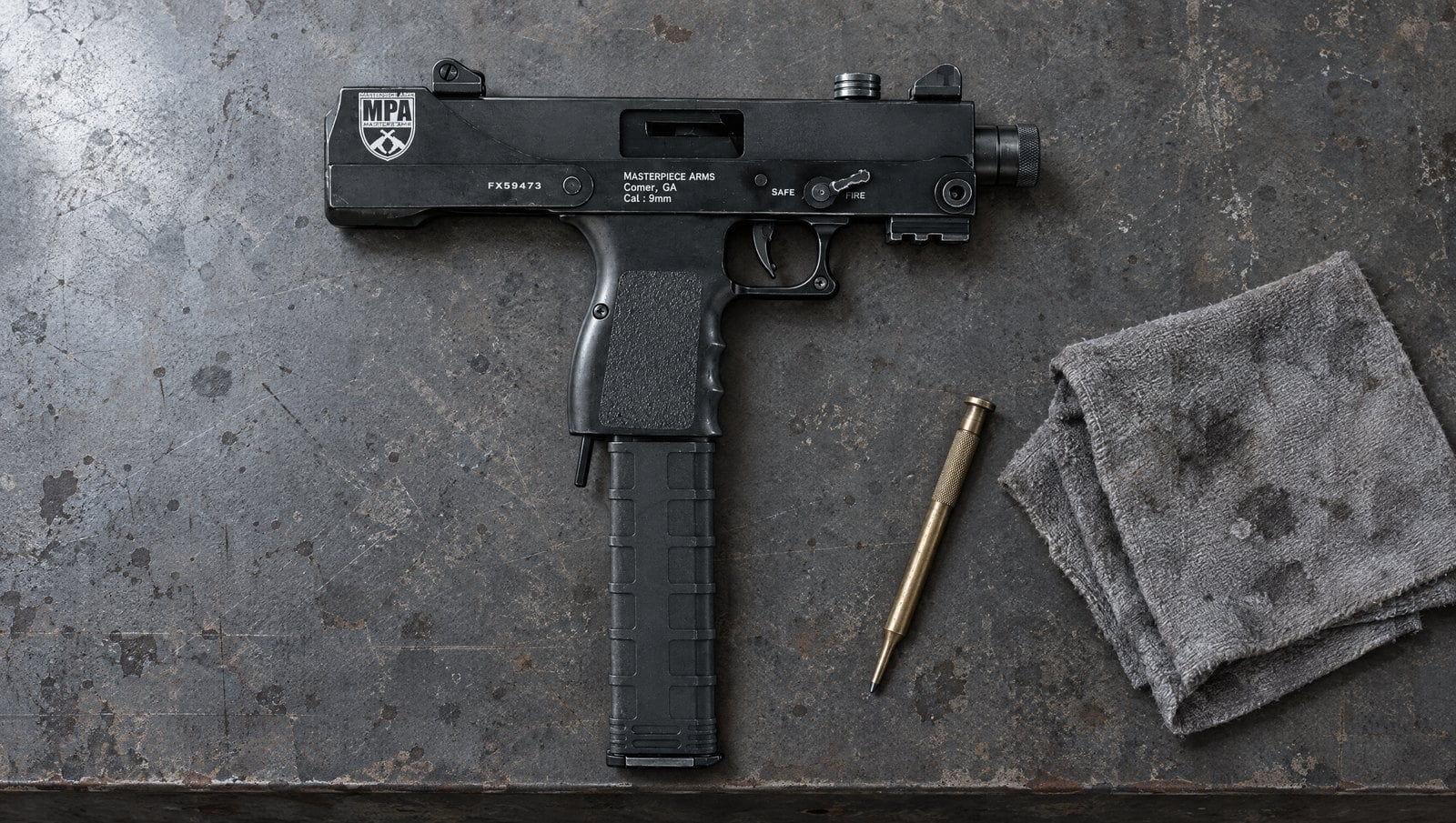Masterpiece Arms Defender MPA30T 9mm top-cocking MAC-10-style pistol with a 30-round magazine on a concrete shop bench