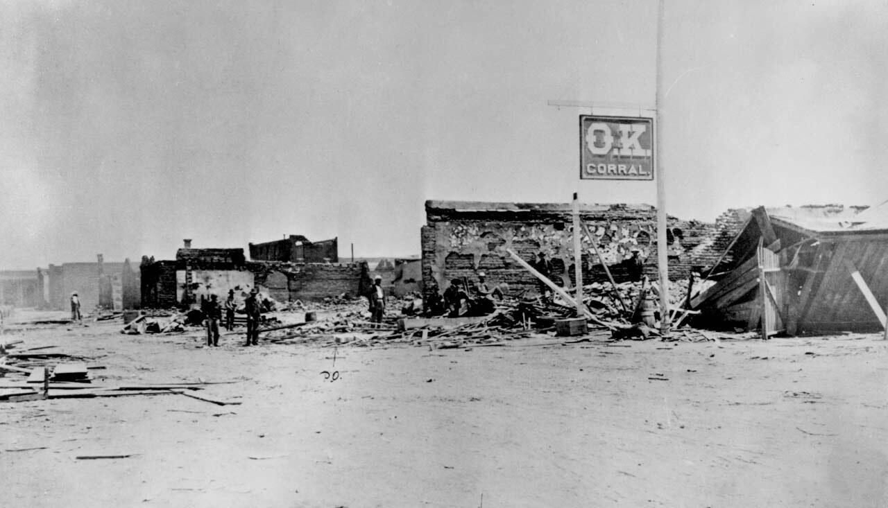 The O.K. Corral sign standing among burned buildings in Tombstone, Arizona, in 1882