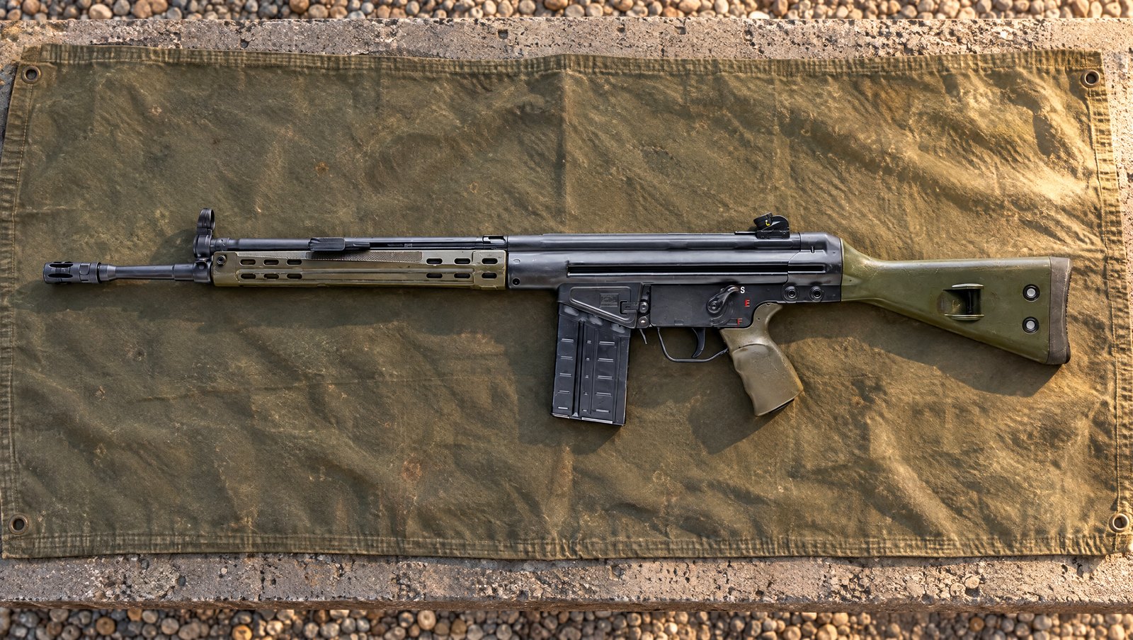 PTR GI .308 roller-delayed rifle with green furniture lying flat on a canvas tarp at an outdoor range
