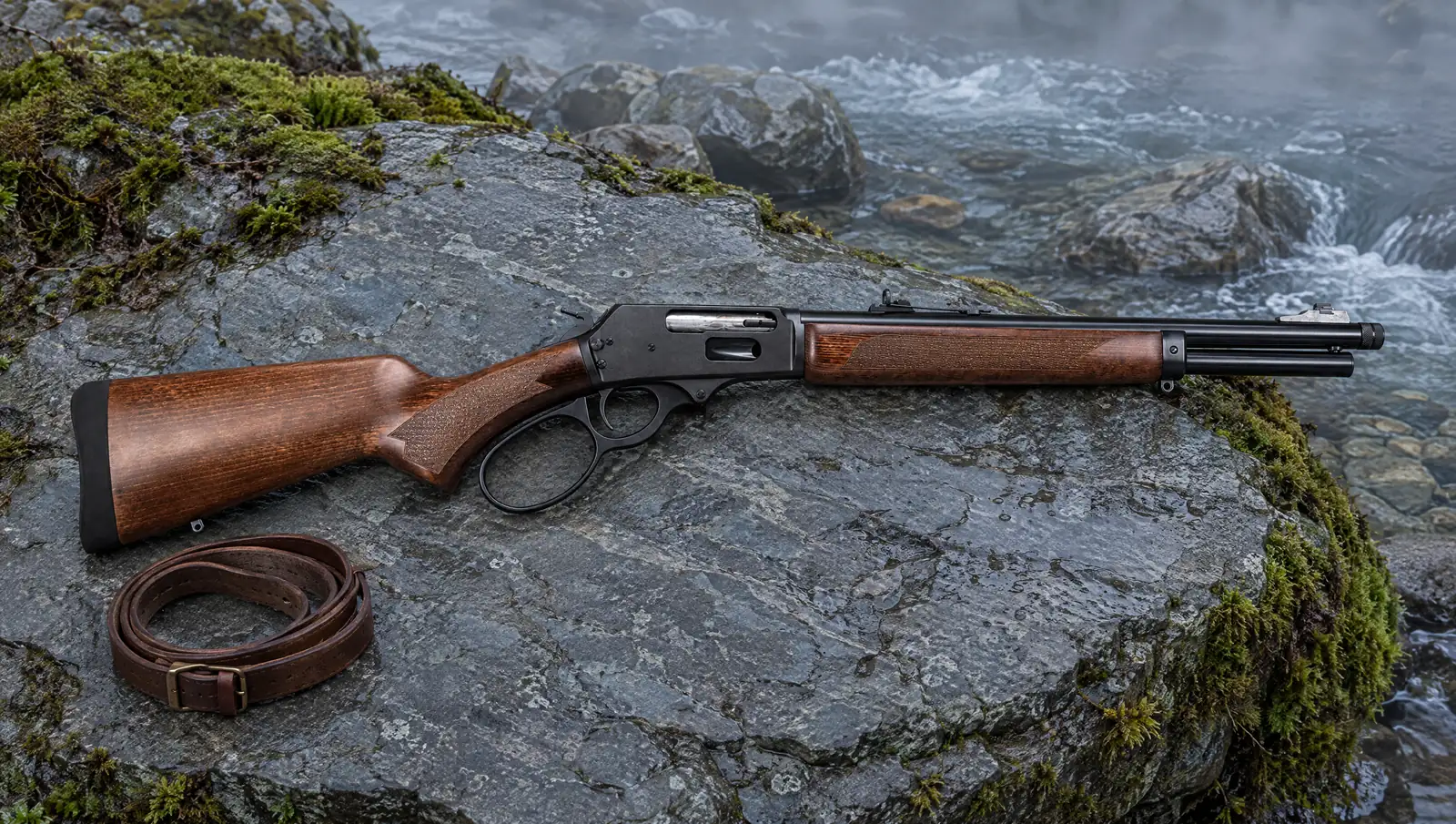 Rossi R95 .45-70 Trapper lever-action carbine with a threaded muzzle cap lying on a flat slate rock beside a misty mountain creek