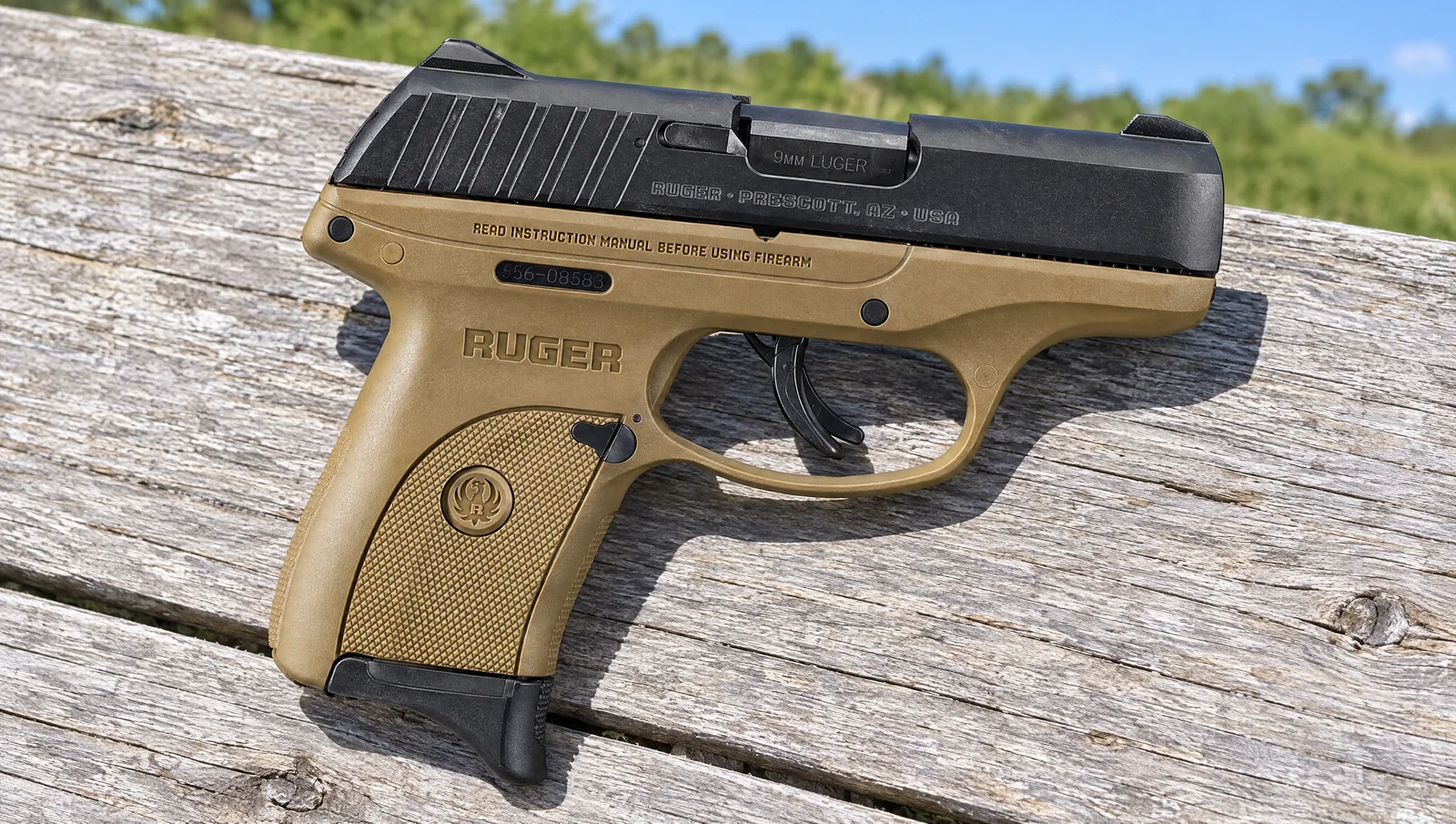 Ruger EC9s with a flat dark earth frame and black slide lying on a weathered gray picnic table in bright sun