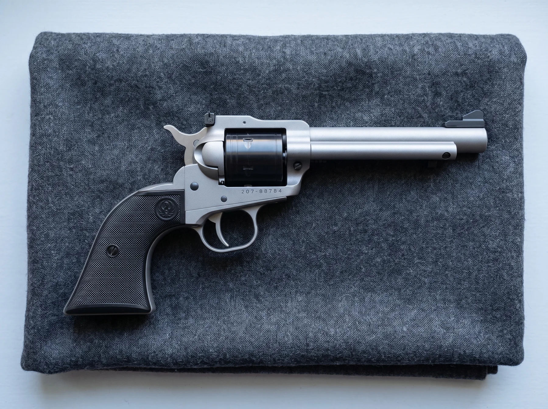 Ruger Super Wrangler 2033 in silver Cerakote with a black cylinder on a gray wool blanket, seen from above