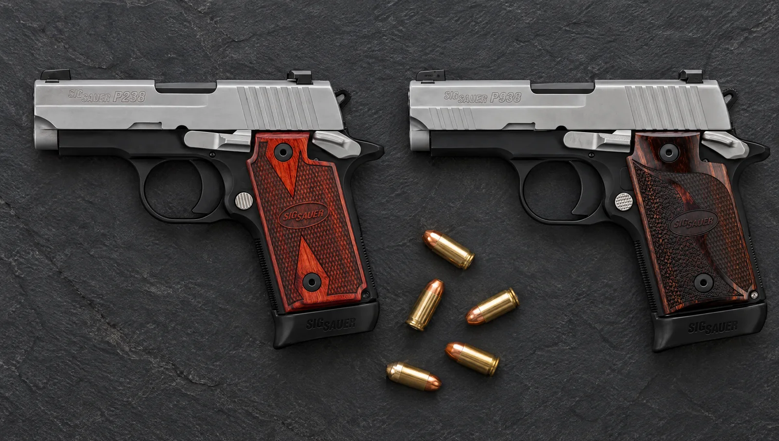 SIG P238 and SIG P938 Two-Tone pistols lying side by side on dark slate with a few loose cartridges between them